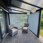 Nowoczesny taras z lamelami RAL 9006DS pion i meblami rattanowymi.