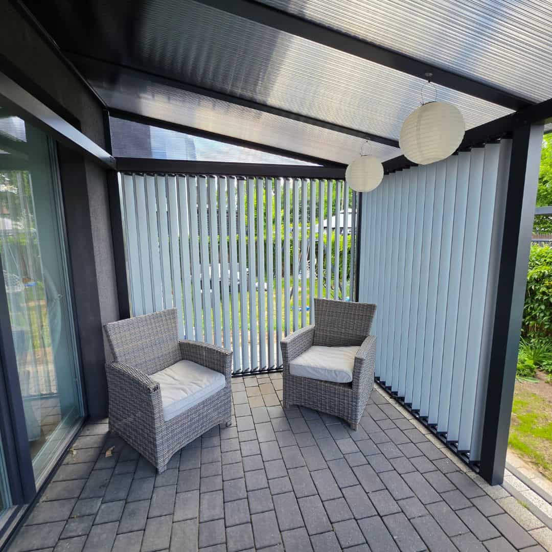 Nowoczesny taras z lamelami RAL 9006DS pion i meblami rattanowymi.