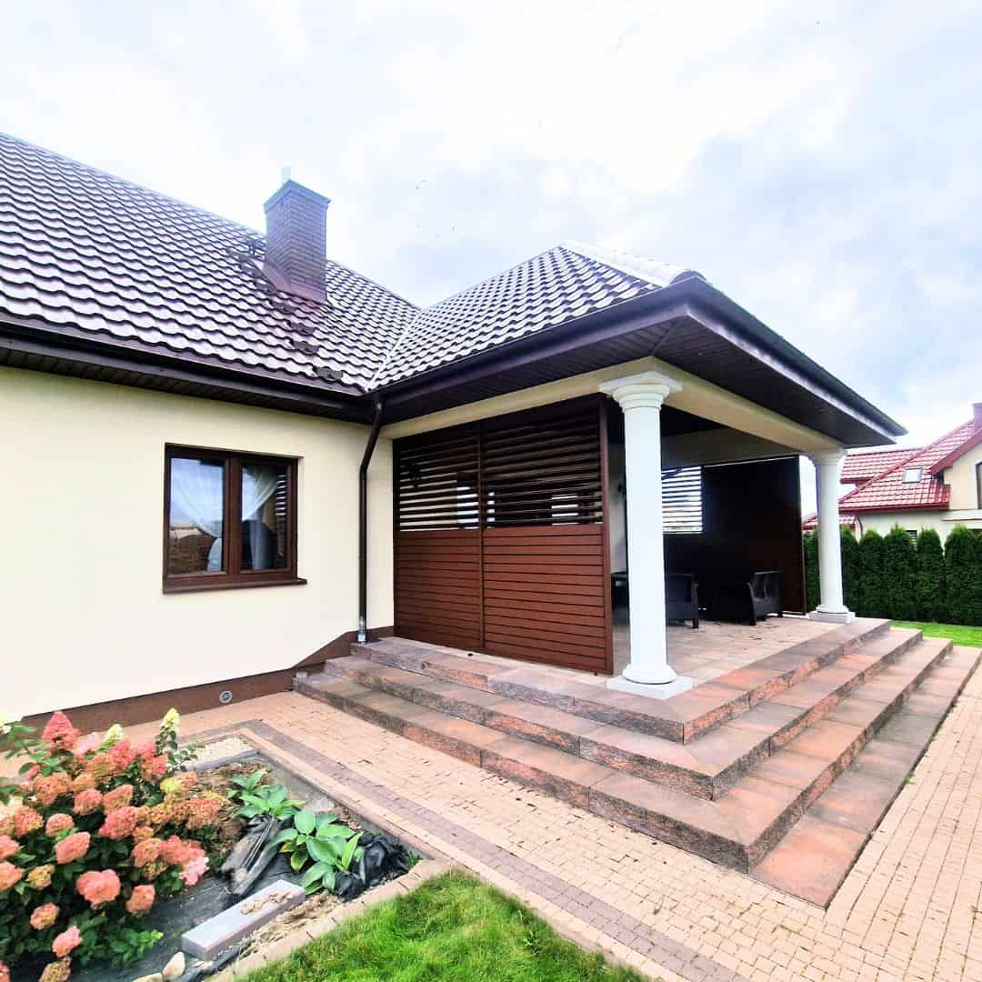 Przesuwna zabudowa tarasu lamele aluminium. Nowoczesny taras z podestem i kolumnami, idealny do relaksu na świeżym powietrzu.