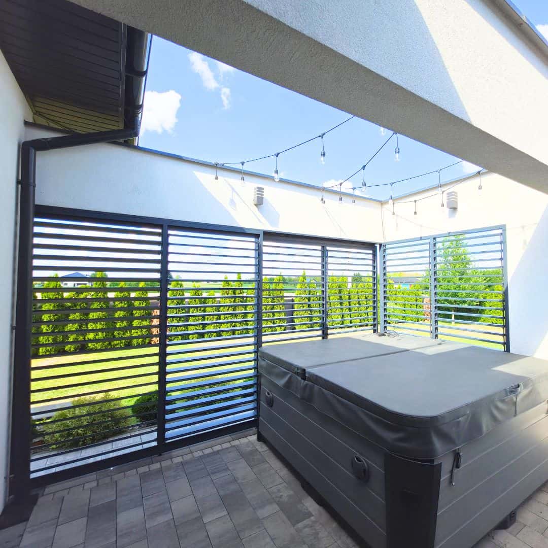 Przesuwna zabudowa tarasu z aluminium . Taras z jacuzzi i oświetleniem na zewnątrz budynku.