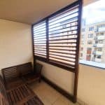 Zabudowa balkonu z drewnianymi lamelami. Balkon z drewnianymi meblami i osłonami na oknach w nowoczesnym budynku.
