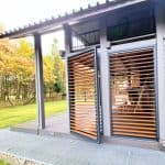 Zabudowa boczna tarasu z lamelami poziom aluminium. Nowoczesny budynek z drewnianymi żaluzjami i dużym tarasem na zewnątrz.