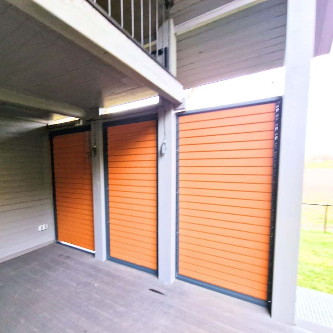 Zabudowa boczna tarasu z lamelami poziom aluminium. Przedpokój z żaluzjami zewnętrznymi w kolorze pomarańczowym.