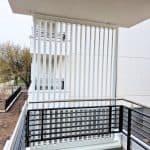 Zabudowa balkonu aluminiowa pion RAL 9016. Nowoczesny balkon z białymi i czarnymi elementami dekoracyjnymi.