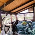 Zabudowa tarasu aluminium RAL 8015 DS poziome lamele. Przytulny balkon z drewnianymi ścianami i roślinami w doniczkach.