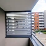 Boczna zabudowa balkonu aluminium RAL 7037. Nowoczesny balkon z żaluzjami aluminiowymi w bloku mieszkalnym.
